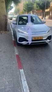 קישוט רכב ברחובות – סרט טול לבן אנכי עם פפיון מרכזי, סידור רכב חתונה אלגנטי על שפת המדרכה